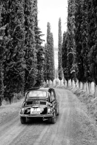 Fiat 500 on a typical street with cypress trees in Tuscany