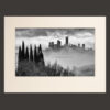 Photo of San Gimignano among the mists next to rows of cypress trees